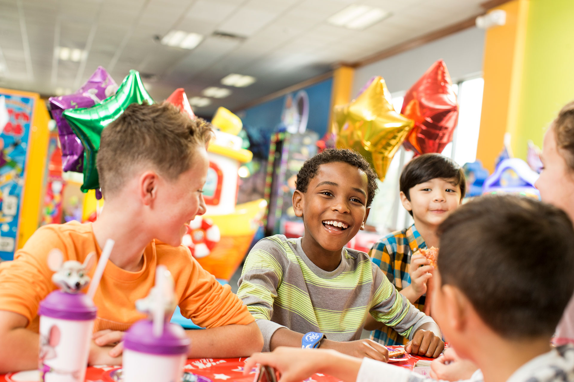 Kids around a table with balloons in the background