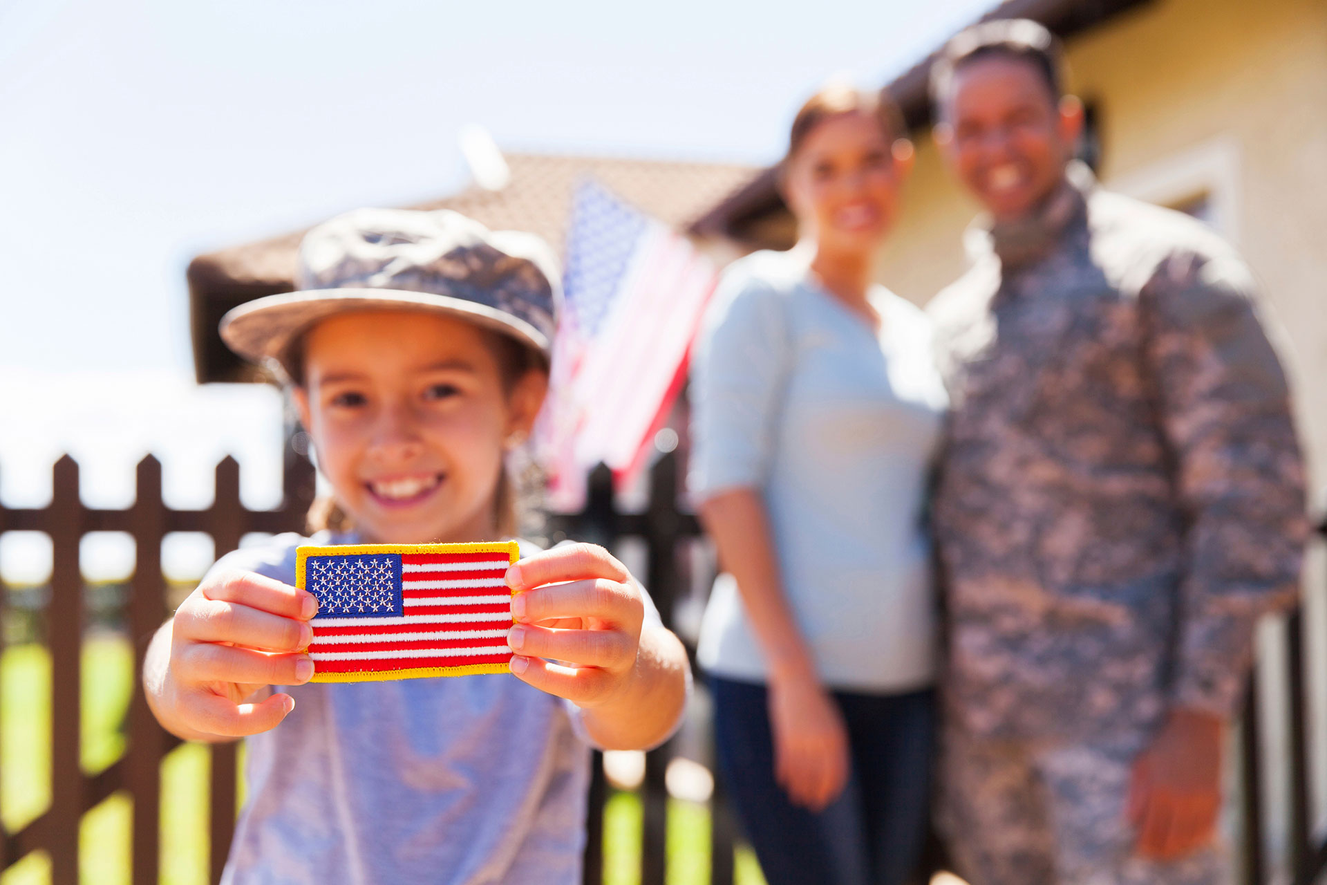 Child holding American flag patch with parents in background
