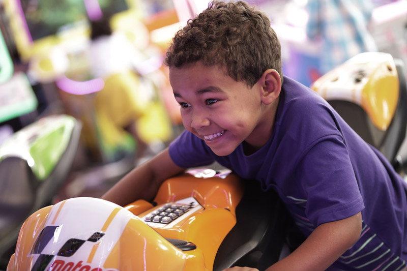 Kid smiling while riding motorcycle arcade game